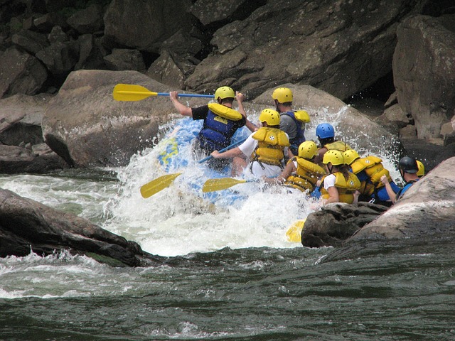Photo d'un groupe de personnes sur un bateau (rafting) : je propose des coachings d'équipes pour travailler la cohésion au sein du groupe.